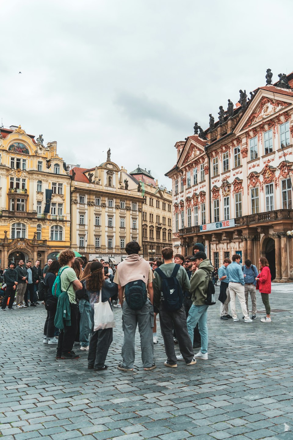 Grupa turystów stoi na zabytkowym europejskim placu.
